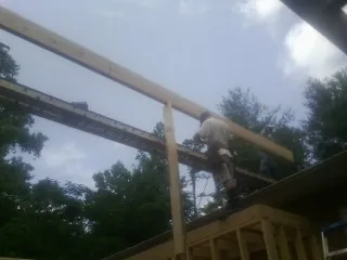 Carpenter setting a ridge beam over a new addition frame — Ice Dam Removal by Roofing Brothers in Lillington