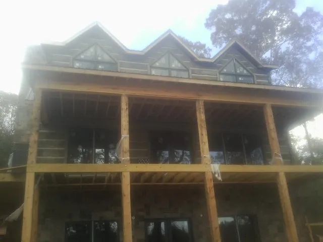 Dormers and porch framing on a large log home under construction — Roof Coating work by our crew in Lillington