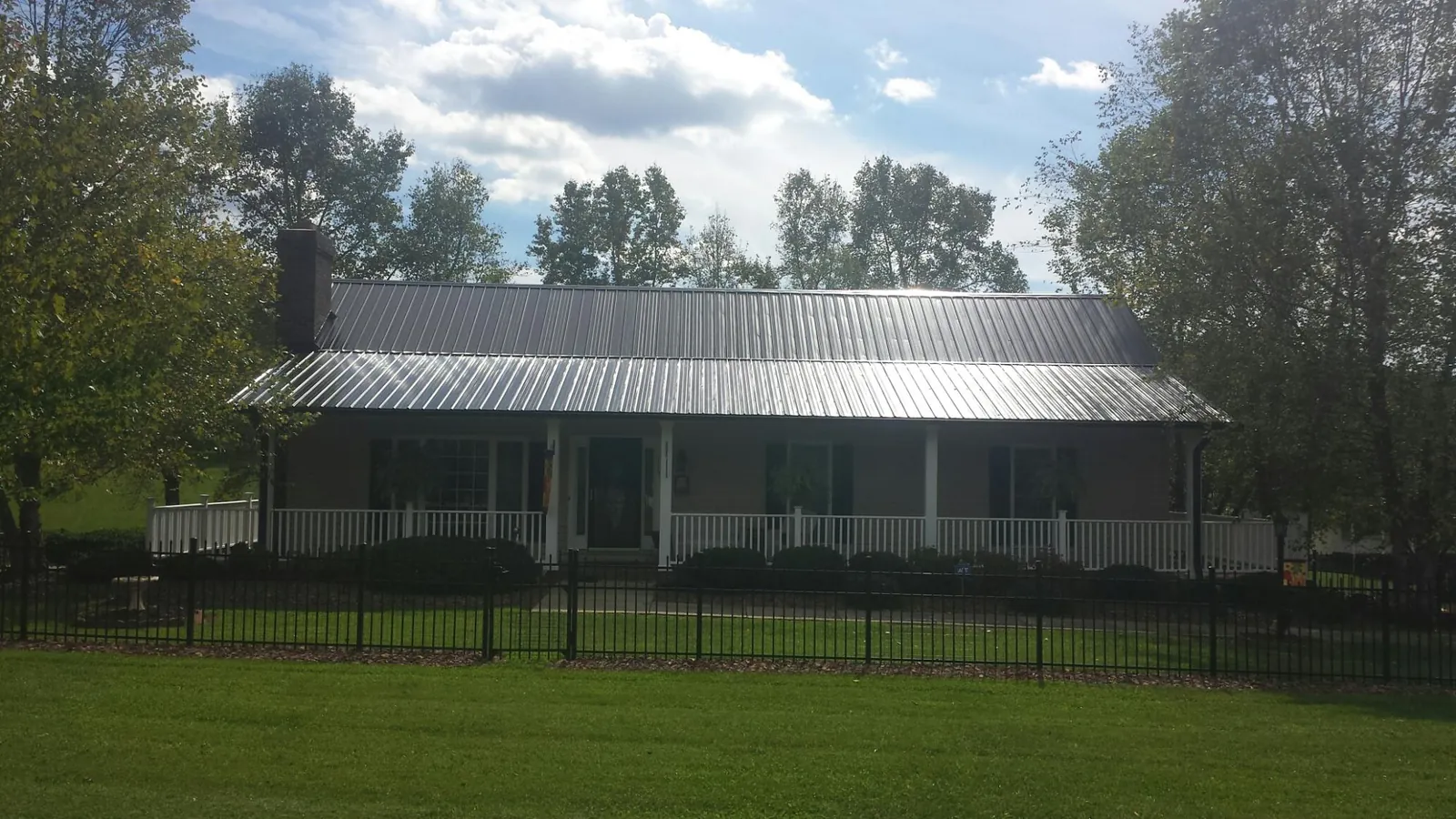 Gray metal roof on a brick ranch with a full width front porch — Gutter Guard Installation work by our crew in Lillington