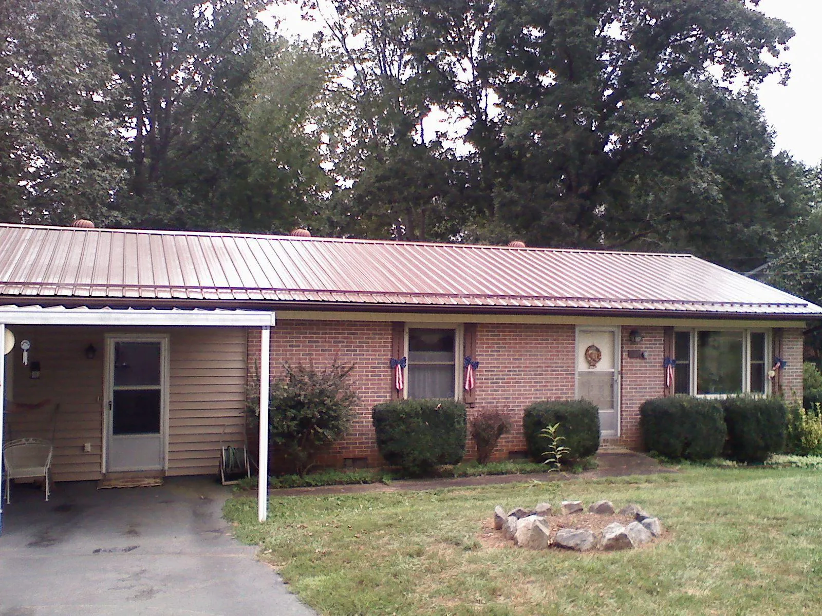 Bronze metal roof and carport on a brick ranch home — Roof Repair work by our crew in Lillington