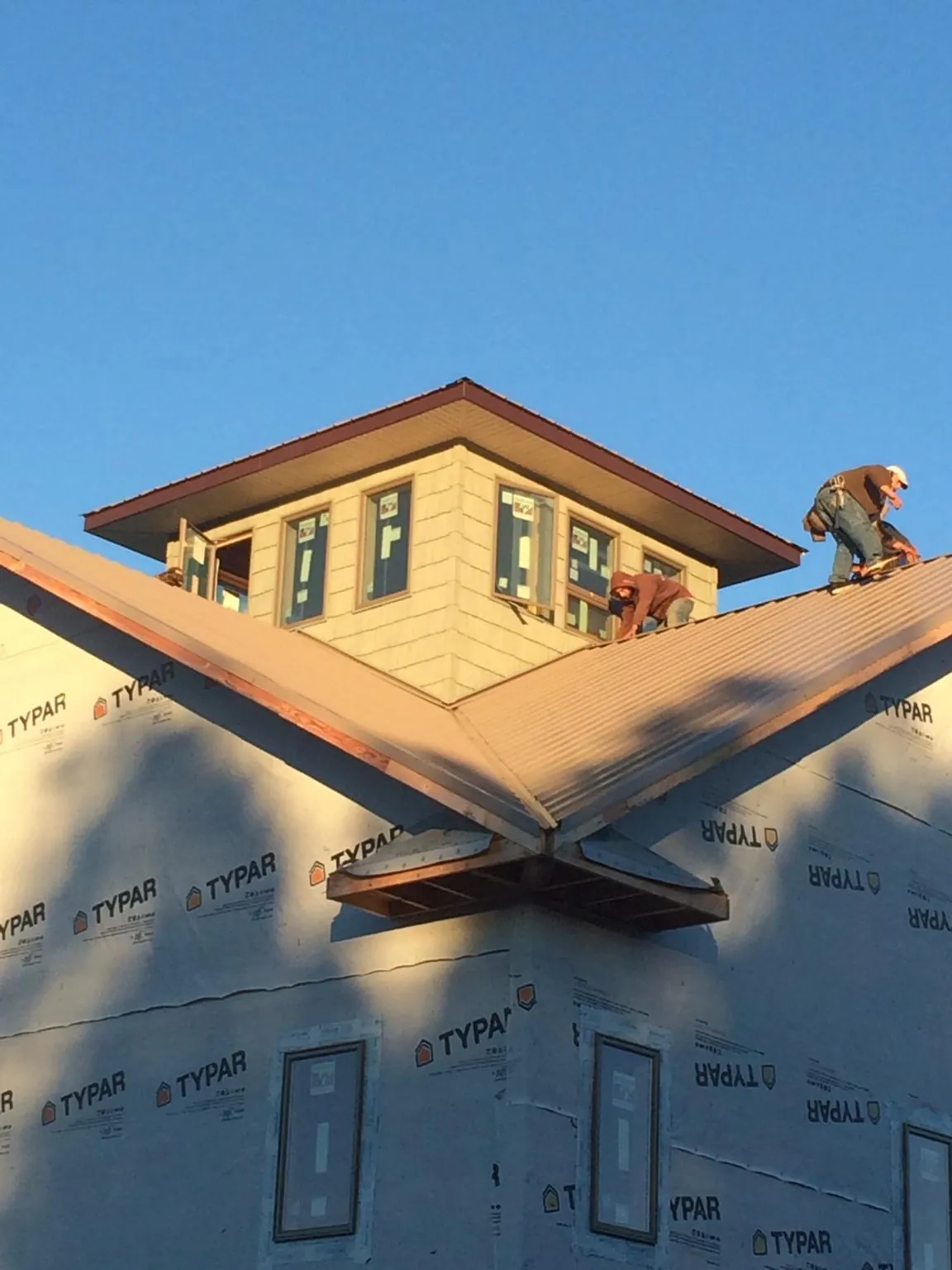 Roofers working around a rooftop cupola on a new metal roof at sunset — Roof Waterproofing in Lillington by Roofing Brothers